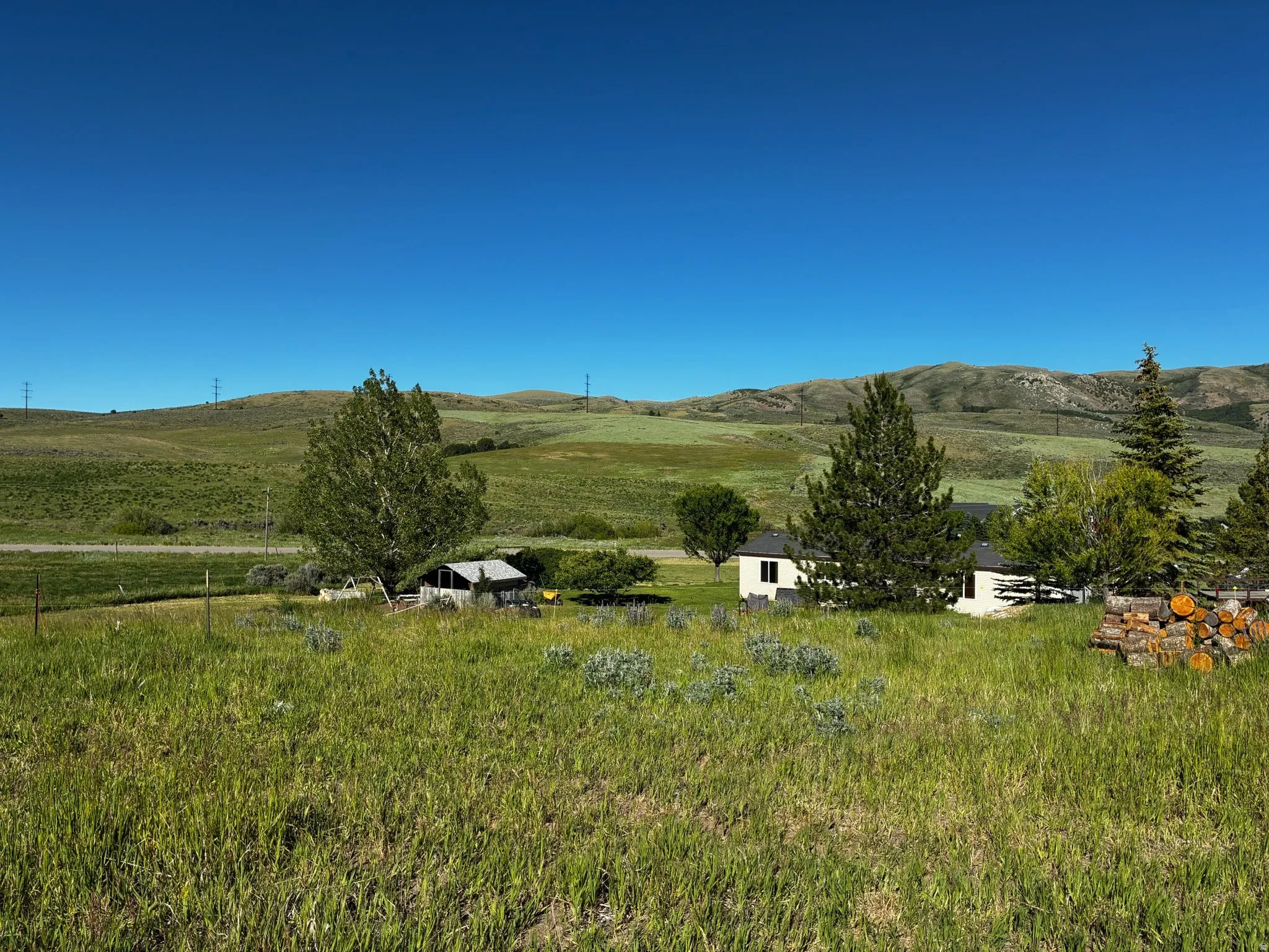 View from back of property. Expansive grassy acreage featuring distant rolling hills, mature trees.