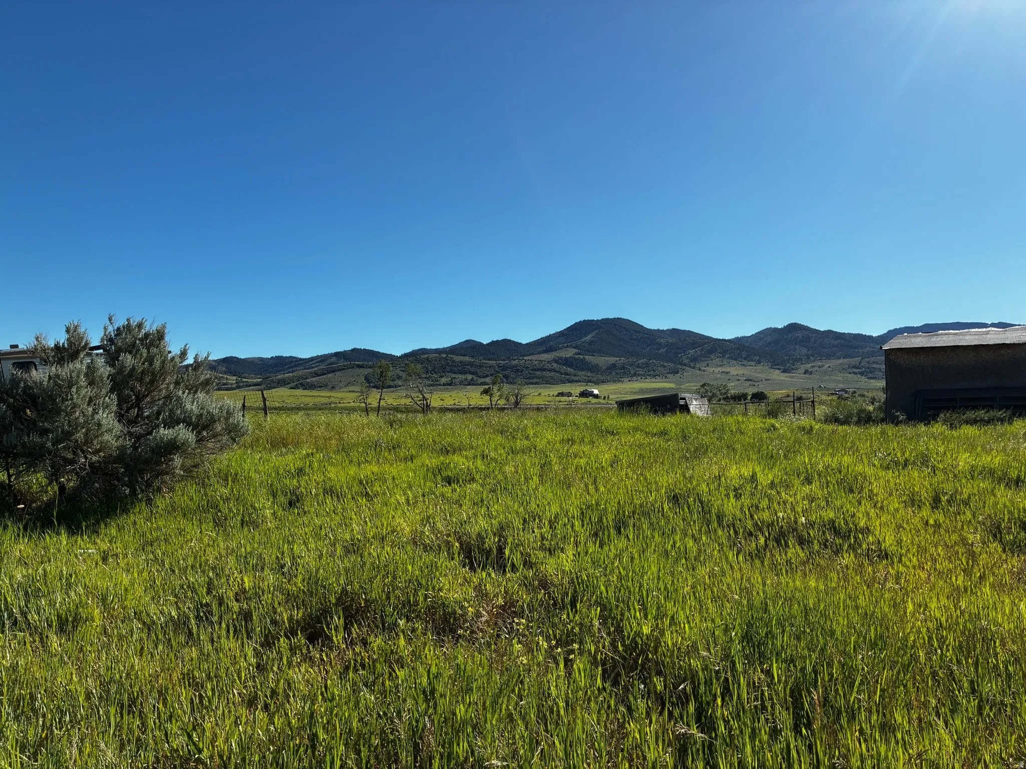 View of mountains to the west.  Expansive green pasture with a mountainous backdrop.