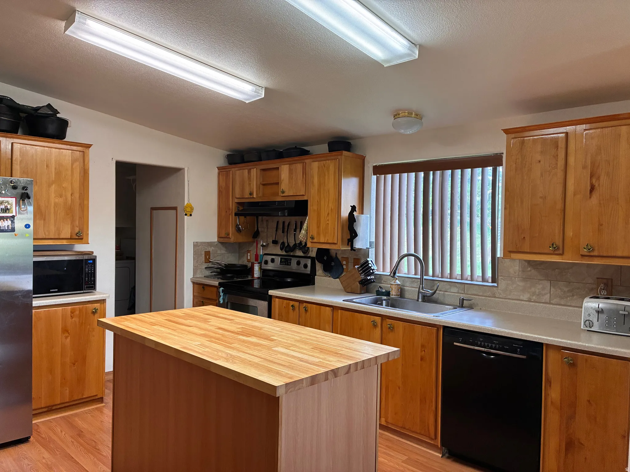 Kitchen with built-in dishwasher, wood cabinets and access to laundry room/mudroom.