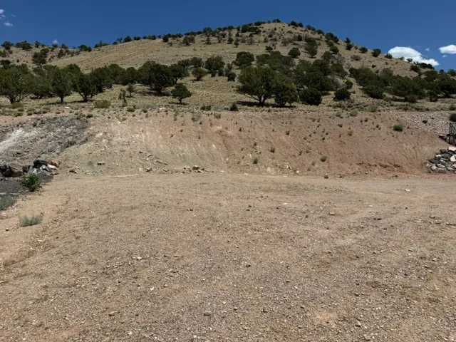View from front of lot facing north.  This expansive vacant lot features a gravel surface, surrounded by rolling hills.