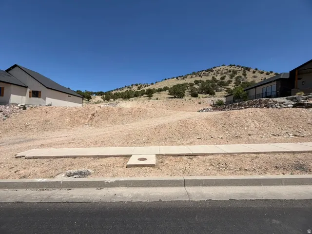 Facing North.  Cleared building site featuring a paved road, concrete curb, sewer, and sidewalk.