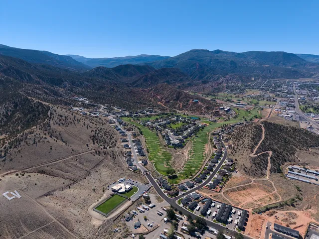 Aerial overview of a residential community with a golf course, surrounded by mountainous terrain