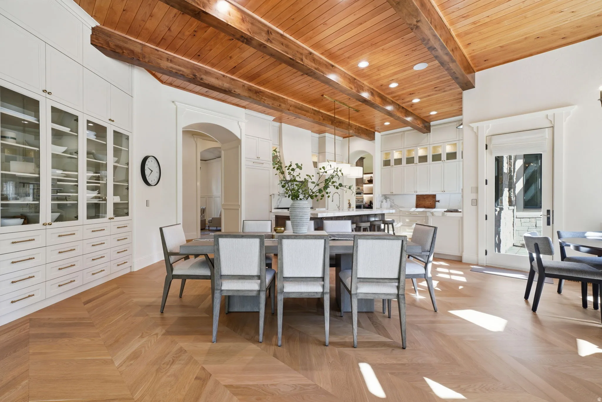Herringbone wood-finish flooring complements a wooden plank ceiling with exposed beams