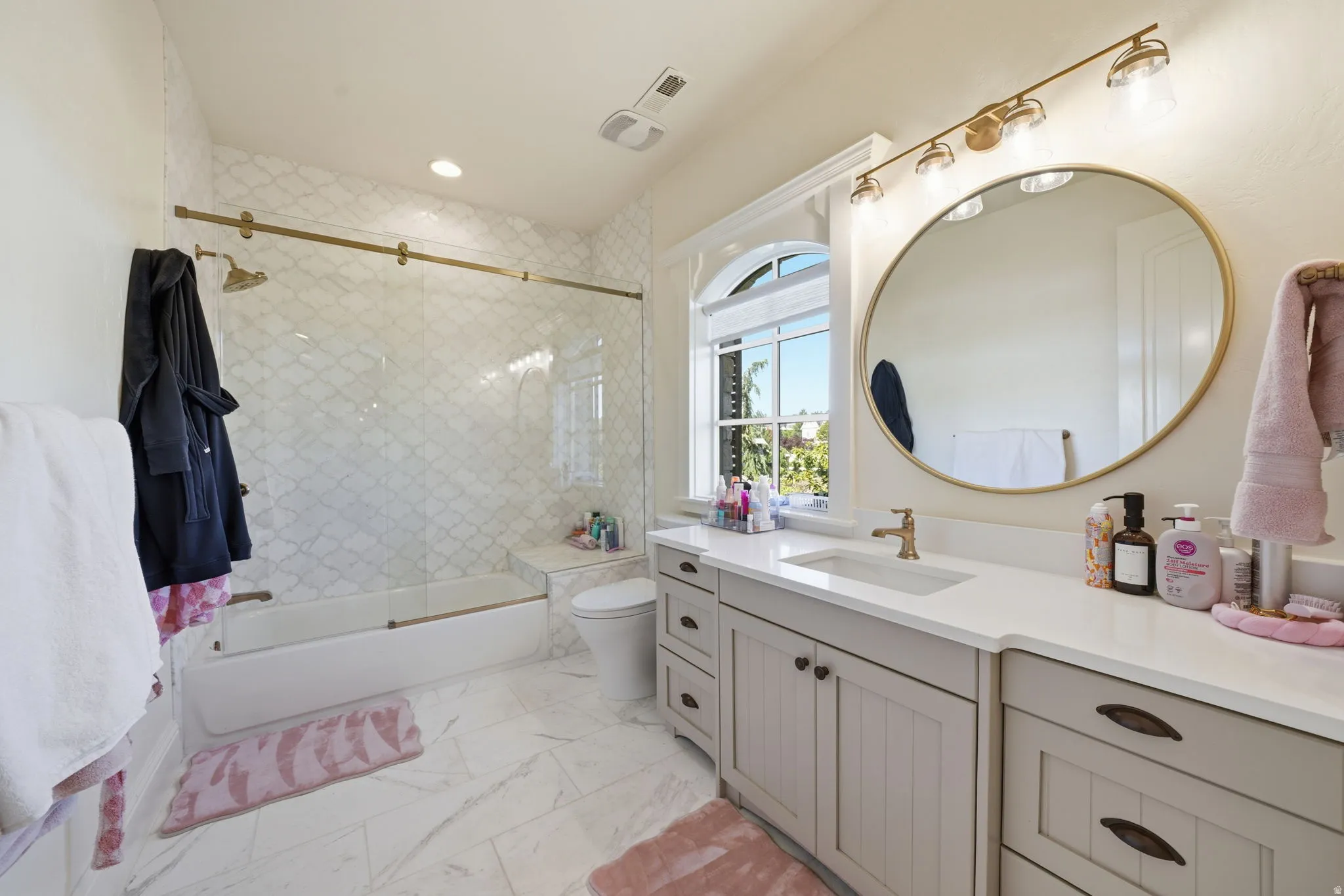 Contemporary bathroom featuring a tub-shower combination with a sliding glass door, patterned tile surround, and built-in bench