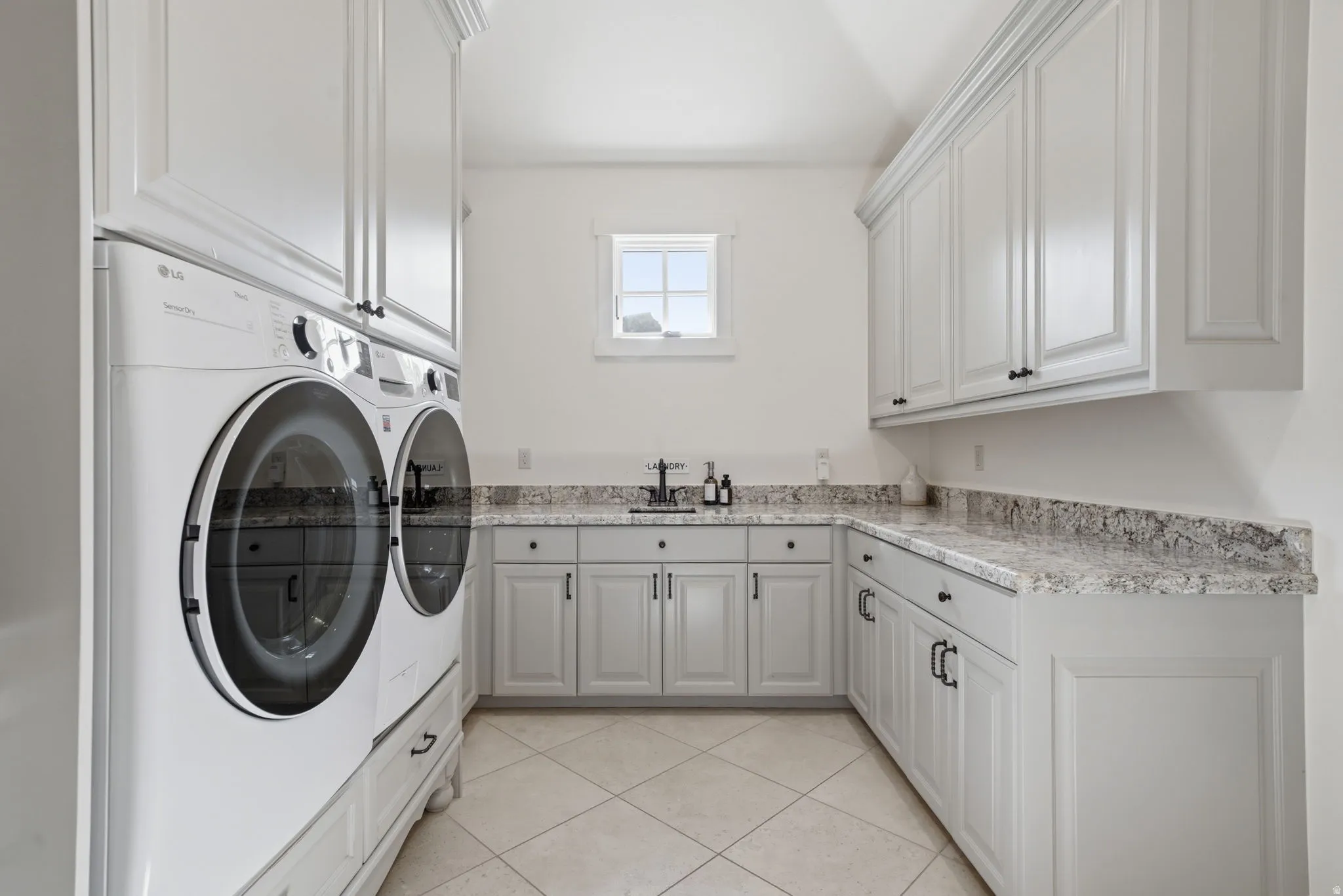 Laundry area featuring L-shaped cabinetry, light-toned countertops, and a window