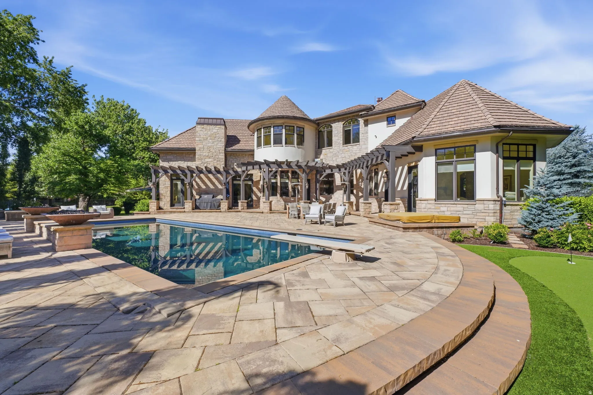 Expansive paver patio with an in-ground swimming pool and diving board