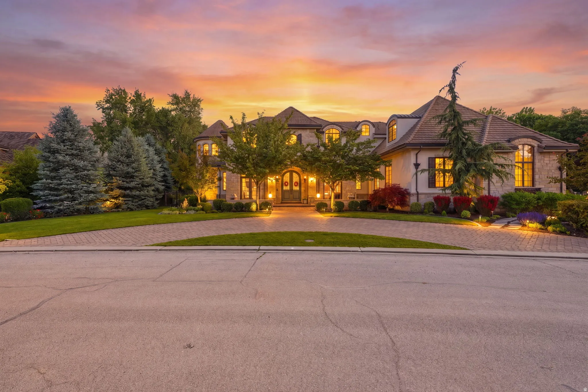 Stately exterior featuring stone and stucco finishes, a multi-gabled roofline, and a prominent arched entryway