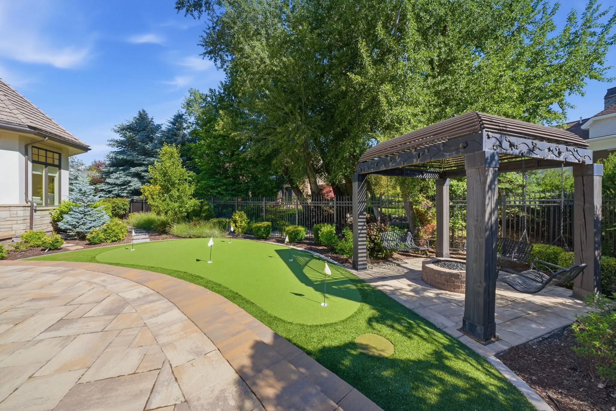 Putting green with multiple cups, surrounded by a stone paver patio