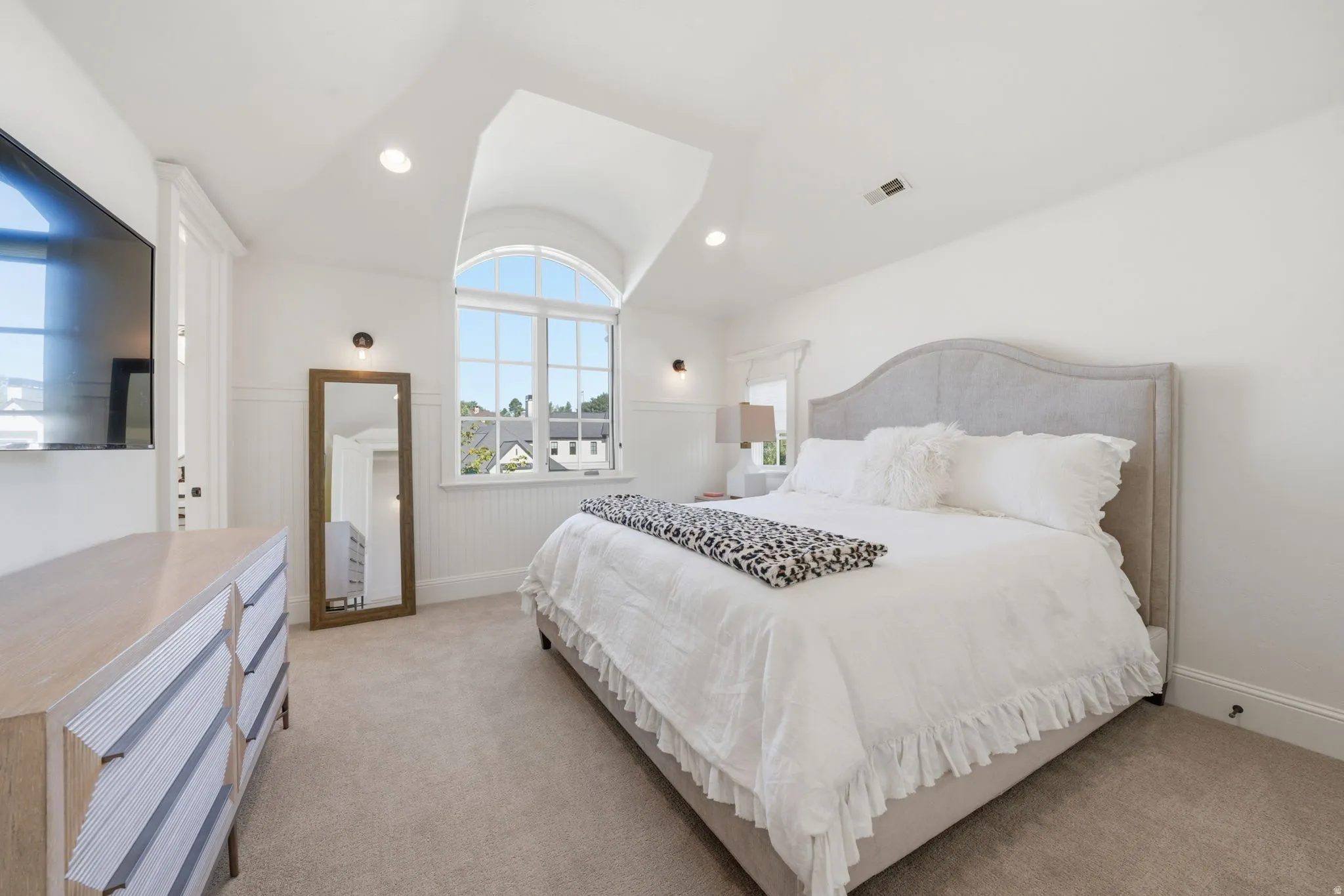 Vaulted ceiling bedroom featuring an arched window, recessed lighting, wall-mounted sconces, and neutral carpet flooring