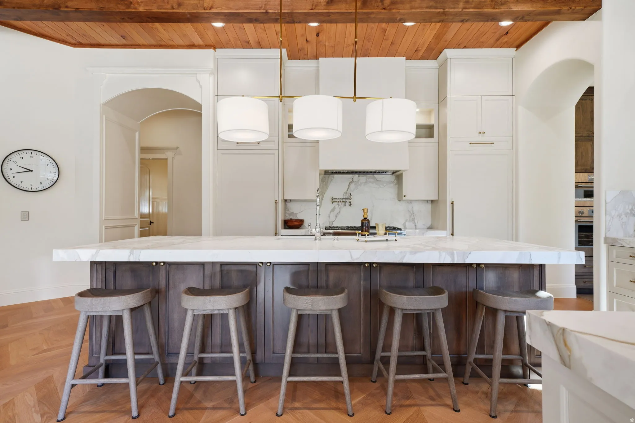 Spacious kitchen featuring an oversized island with seating, a marble-patterned countertop and backsplash, a professional-grade range, and paneled appliances
