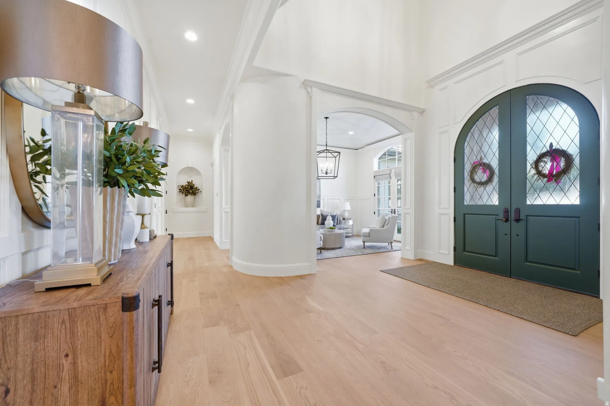 Grand entryway featuring light wood-finish flooring, tall ceilings, and an arched double entry door with leaded glass