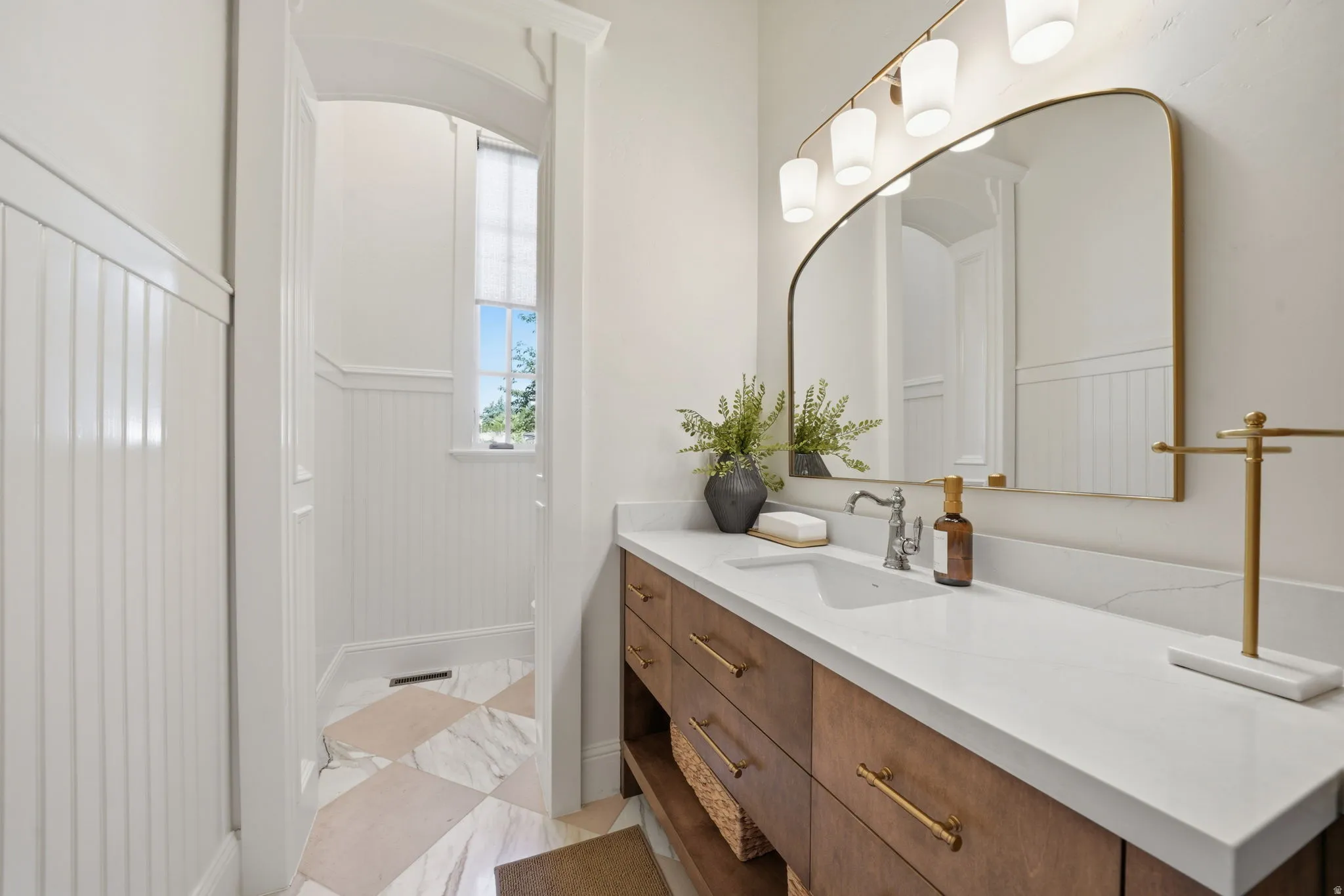 Bathroom vanity featuring a single undermount sink, a white countertop, and a wood-finish cabinet with brass hardware