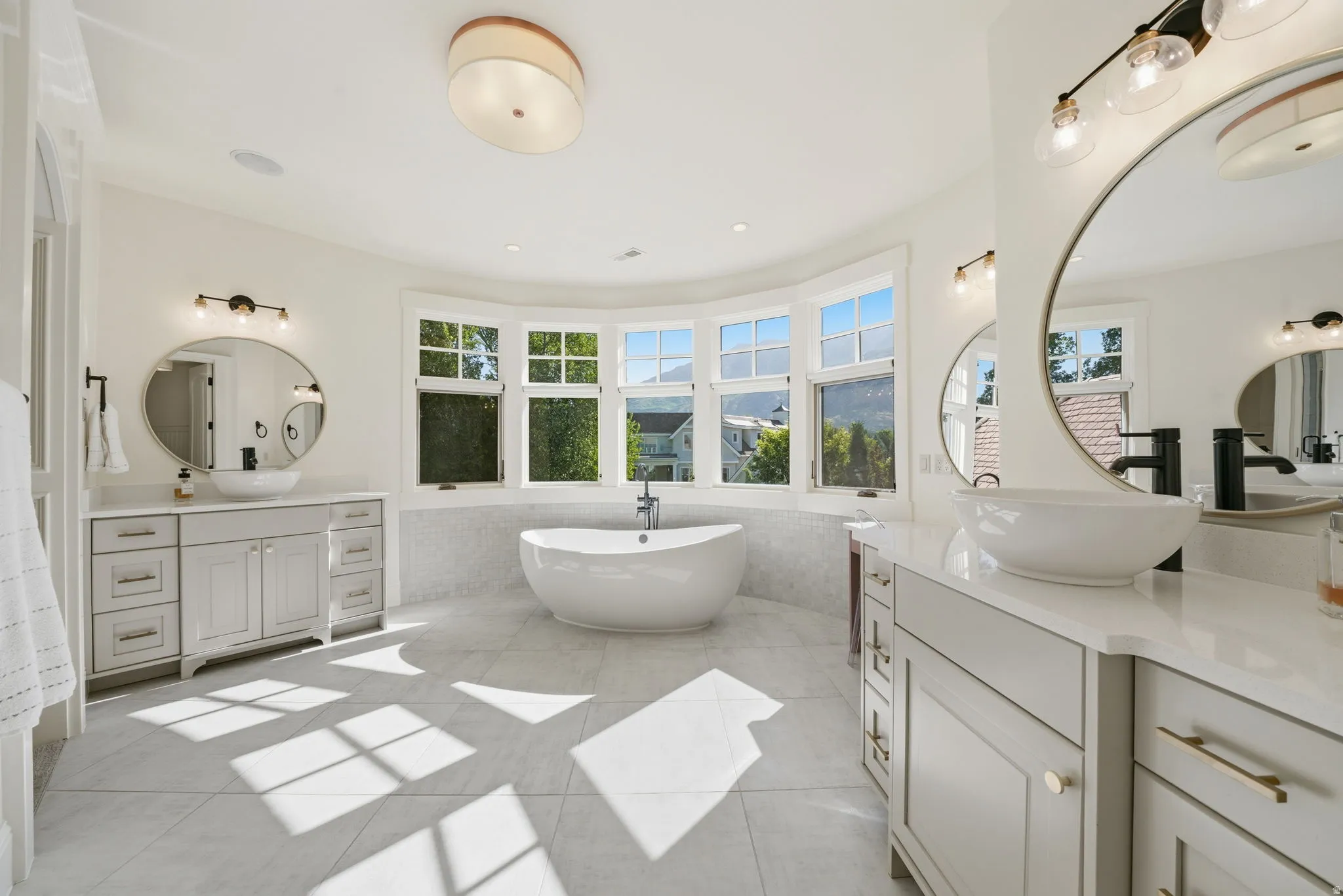 Freestanding soaking tub centered under a curved bay window