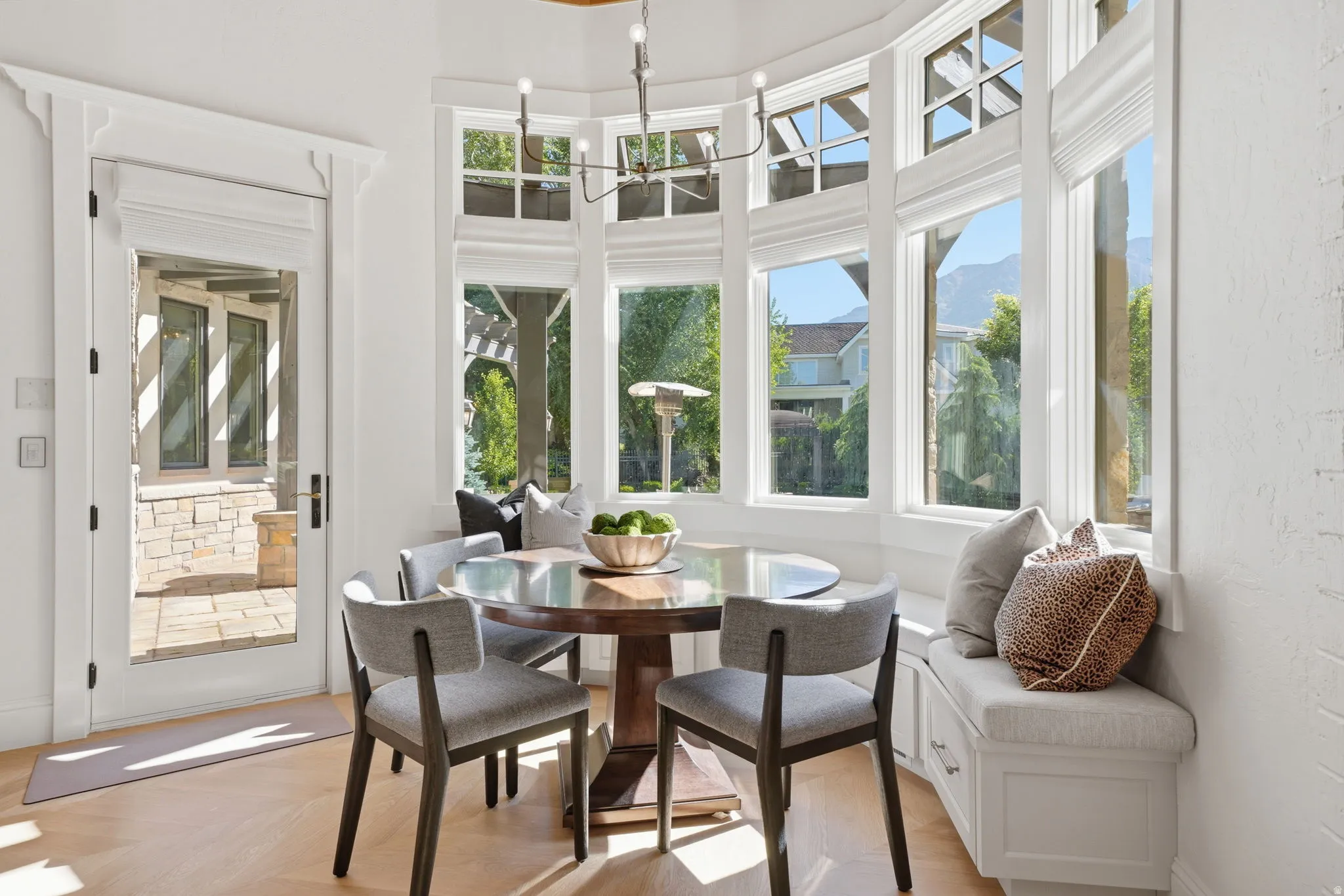 Bay window dining area featuring a built-in bench with storage, wood-finish flooring, a full-lite exterior door, and a multi-light chandelier