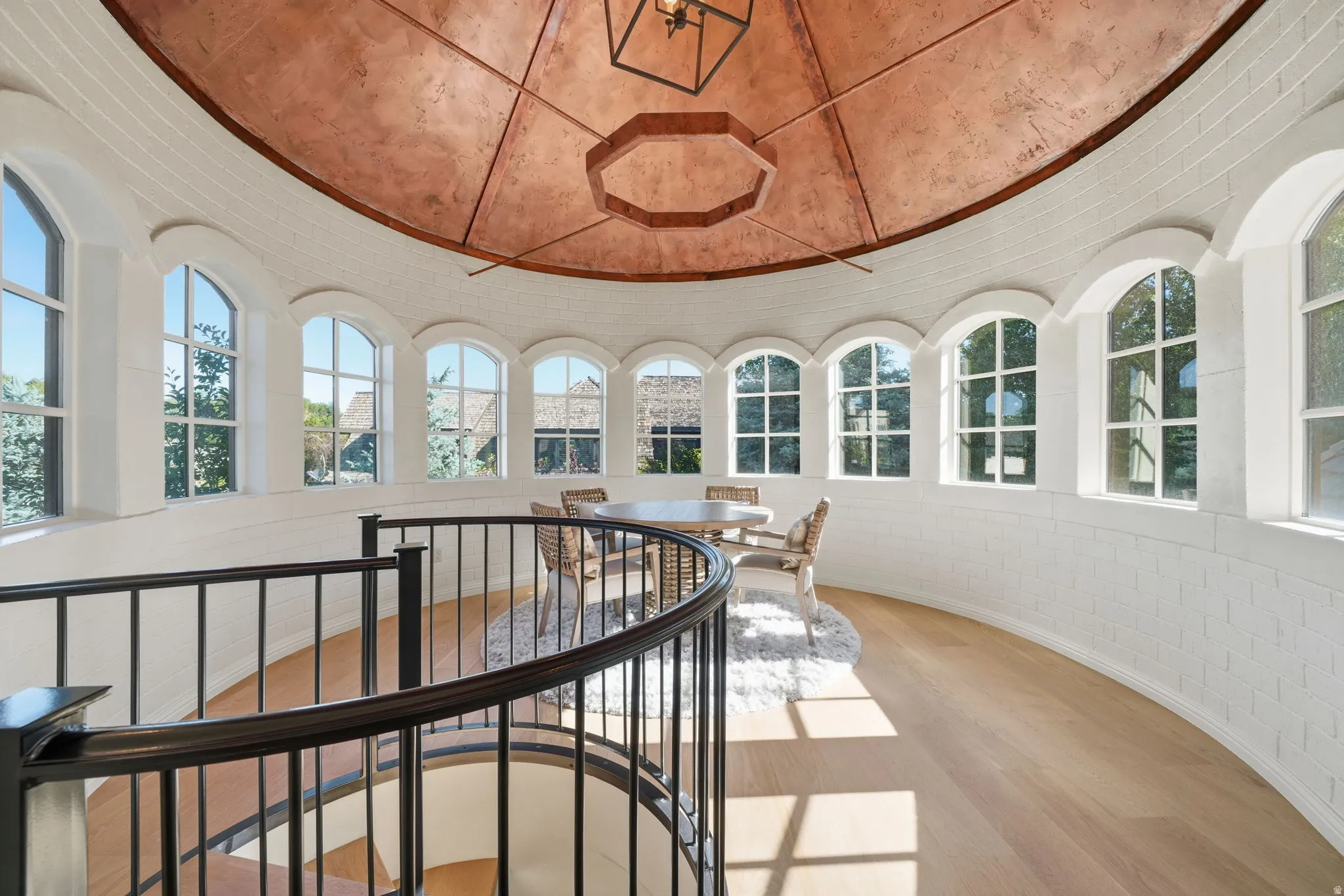 Circular room featuring a copper-finish dome ceiling and a wrought iron spiral staircase