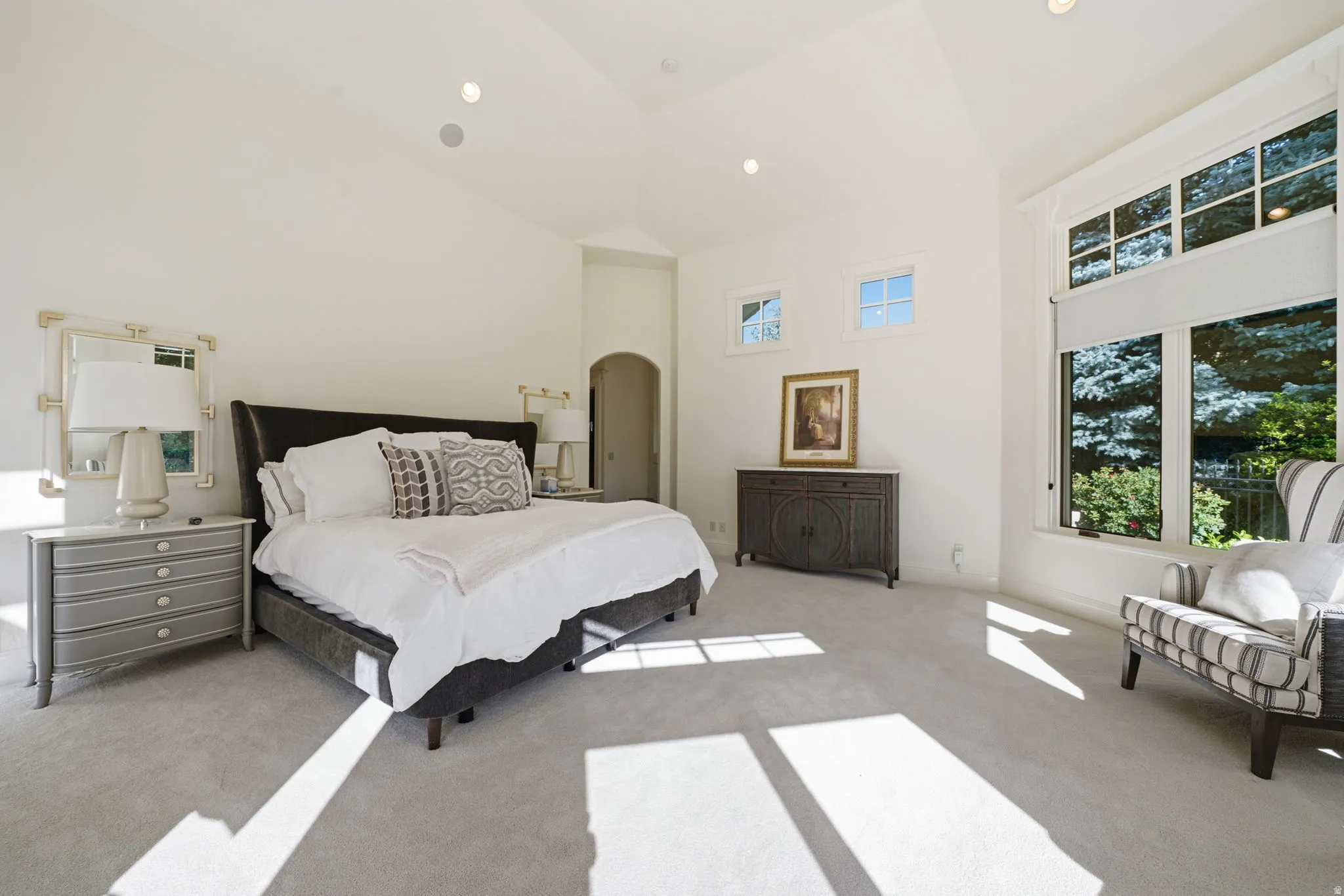 Vaulted ceiling bedroom featuring expansive windows, recessed lighting, wall-to-wall carpeting, and an arched doorway