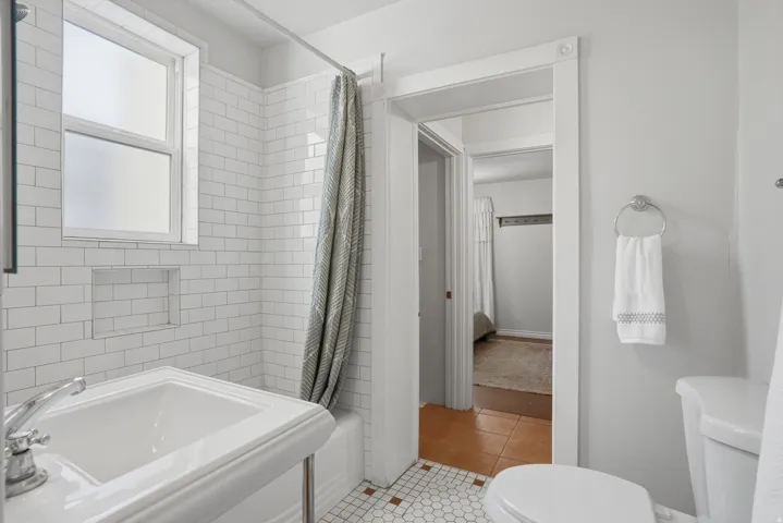 Bathroom featuring white subway tile surround, built-in shower niche, and hex tile flooring