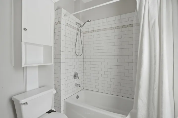 Bathtub and shower combination featuring subway tile surround with decorative accent band