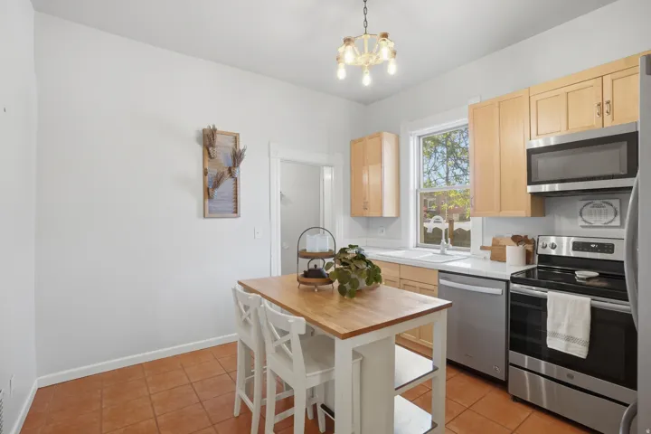 Kitchen featuring neutral cabinetry, stainless steel appliances, a white sink, and a window