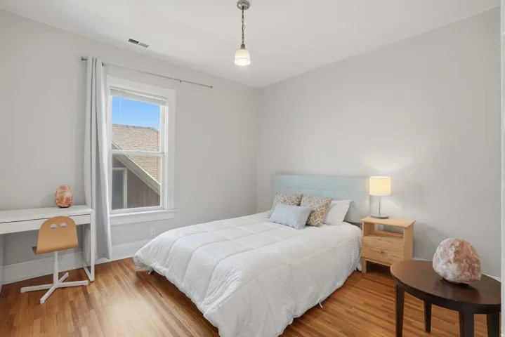 Room featuring wood-finish flooring, a double-hung window with white trim, and light gray wall paint