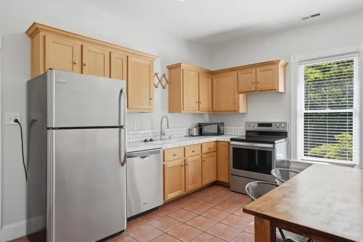 Kitchen featuring light wood cabinetry, white subway tile backsplash, and stainless steel appliances
