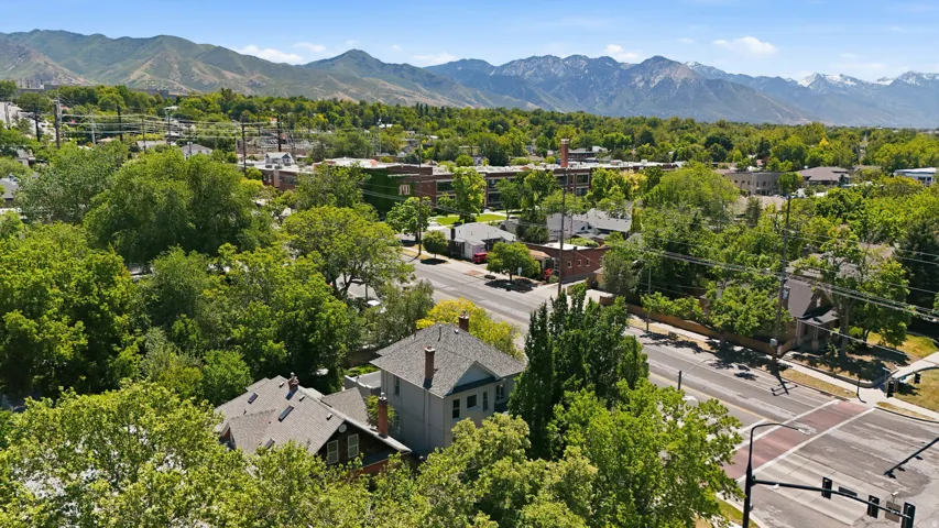 Neighborhood setting featuring mature trees, paved streets, and a mountainous backdrop