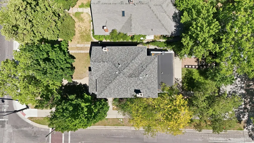 Aerial perspective showcasing a property with a grey shingled roof and a flat black roof section