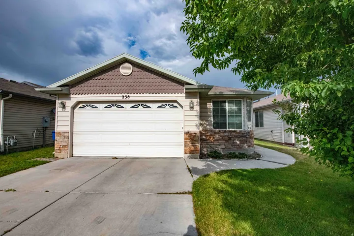 View of front of home featuring an attached garage, driveway, and stone siding