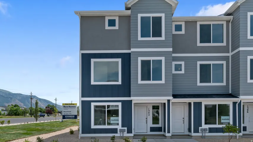 Modern townhouse exterior featuring a multi-tone facade with dark blue vertical siding, light blue horizontal siding, and grey stucco accents