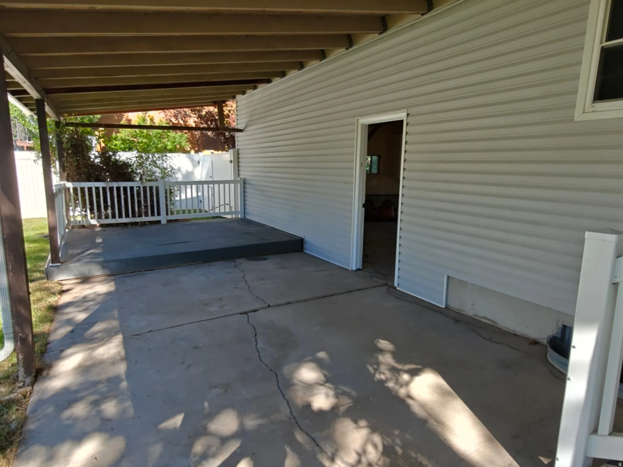 Covered patio area featuring a concrete surface and wood-toned ceiling beams