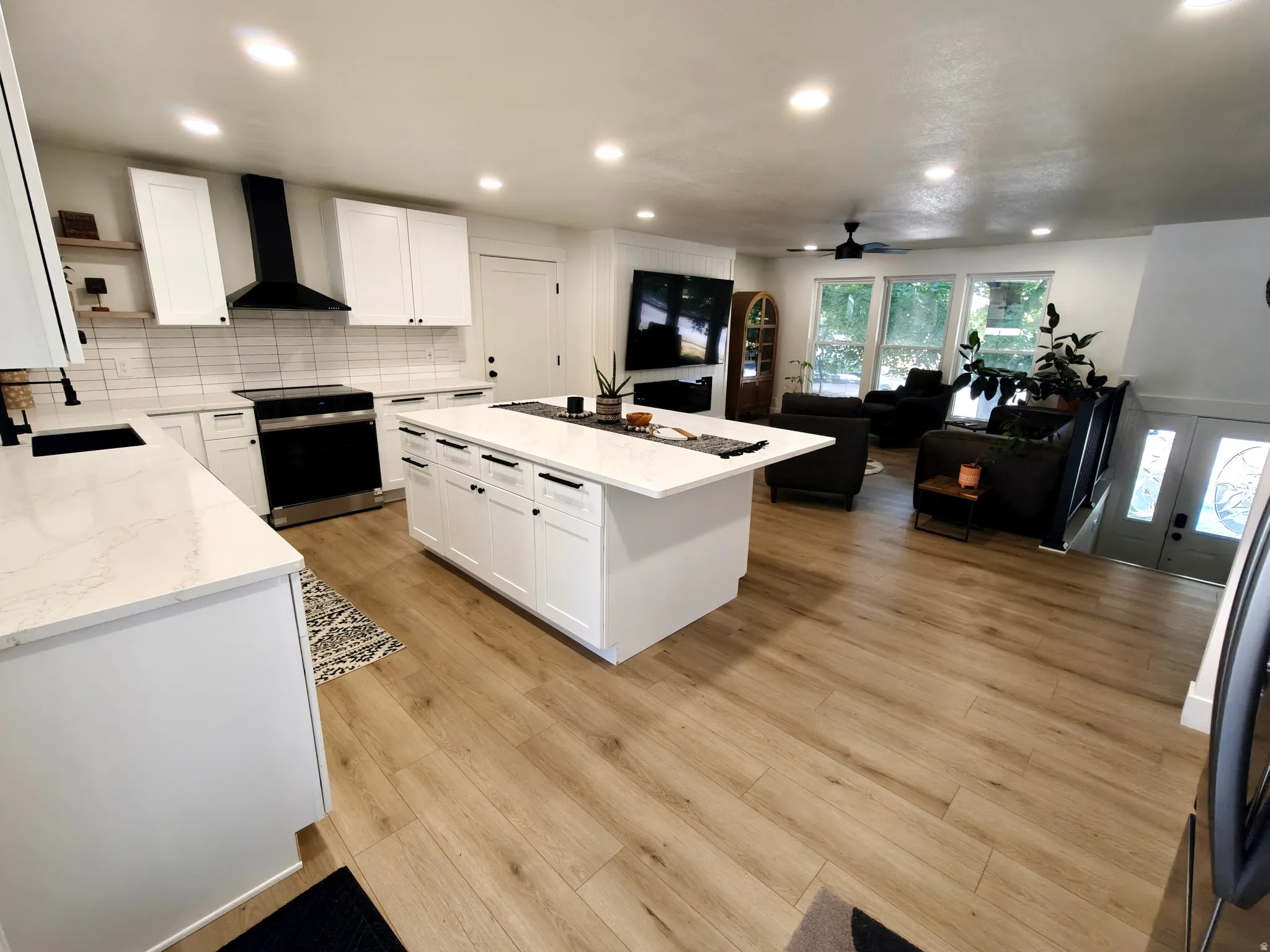 Modern kitchen featuring white cabinetry, quartz countertops, a large center island, wood-finish flooring, and recessed lighting