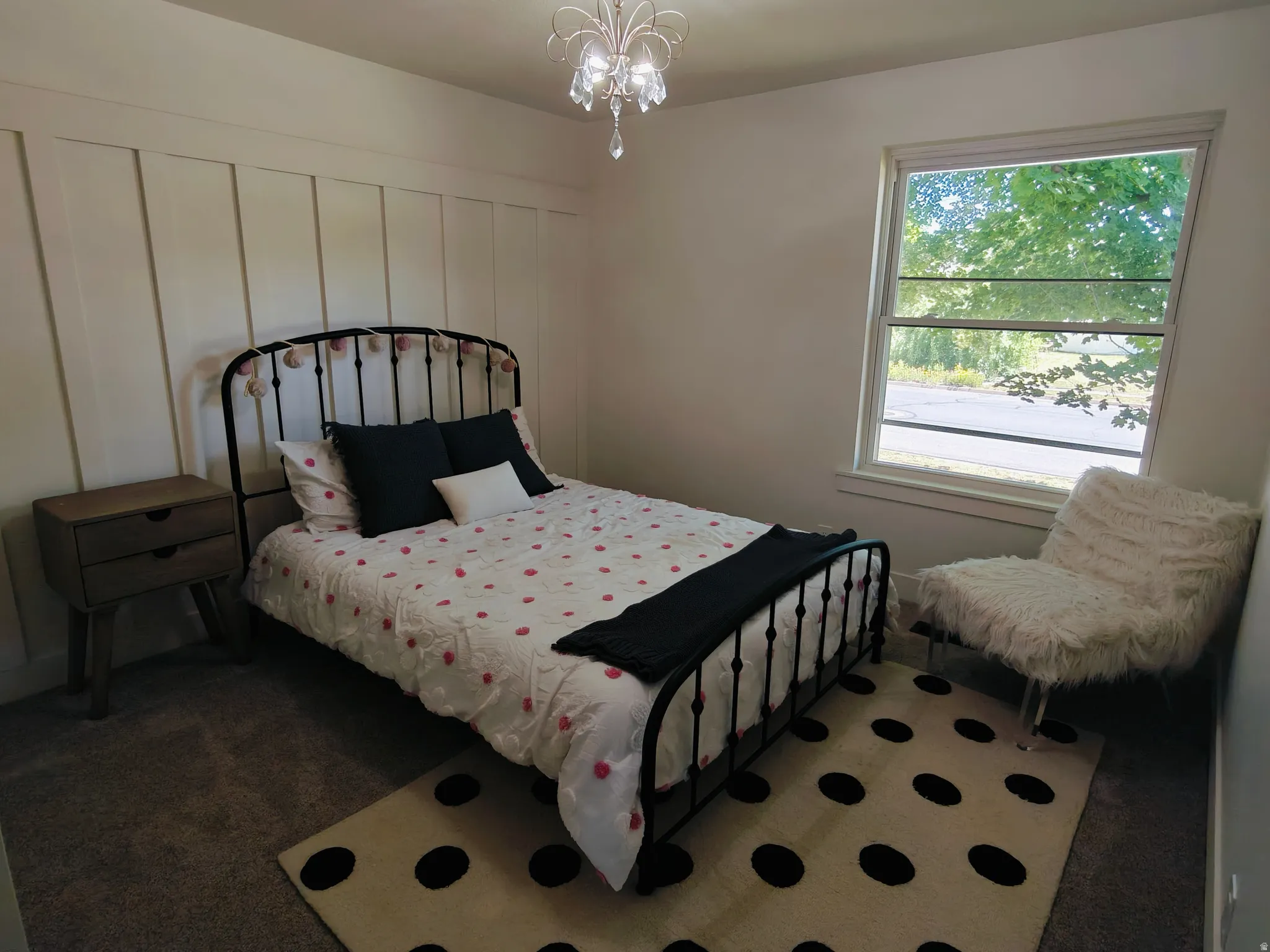 Bedroom featuring wainscoting accent wall, a chandelier light fixture, double-hung window, and carpet flooring