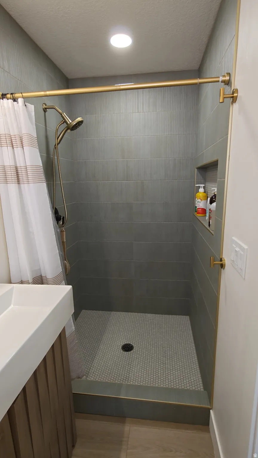 Shower enclosure featuring horizontal gray tile walls and a mosaic tile floor