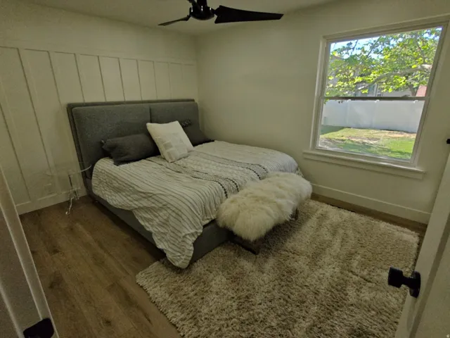 Bedroom featuring wood-finish flooring, a contemporary ceiling fan, and a single pane window