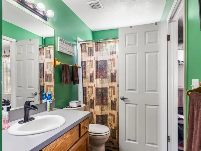 Bathroom featuring a wood-finish vanity with a gray countertop and integrated sink, matte black faucet, and a wall-mounted mirror