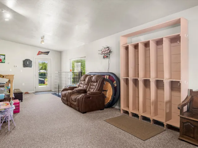 Built-in storage solutions with multiple cubbies and hooks, carpeted flooring, and a glass-paneled exterior door providing exterior access