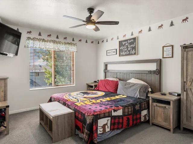 Bedroom featuring light gray carpeting, a window with horizontal blinds, and a ceiling fan with integrated lighting