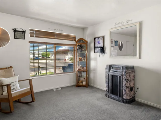Carpeted room with a large window featuring horizontal blinds