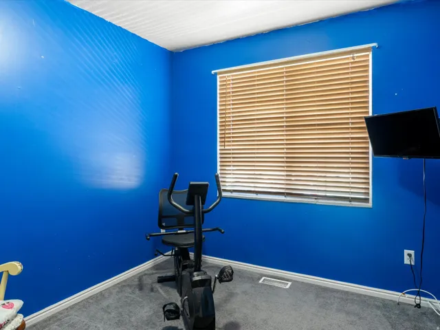 Room featuring blue walls, gray carpet flooring, white baseboards, and a window with horizontal blinds