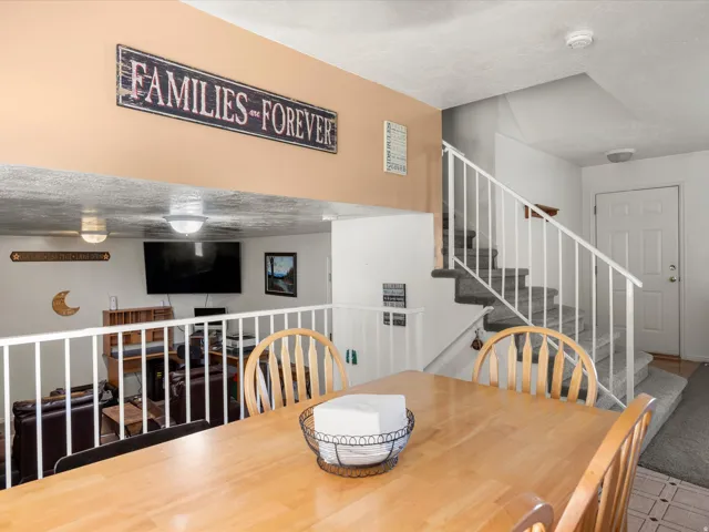 Interior dining area featuring a light wood-finish table and chairs, with a white railing overlooking a lower level
