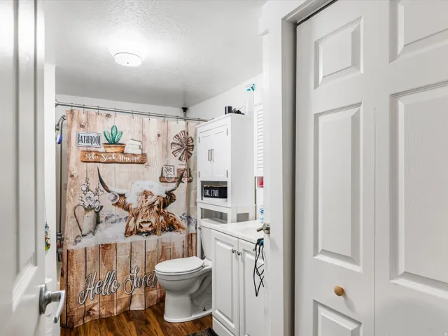 Bathroom featuring a white toilet, white vanity with integrated sink, and white storage cabinetry