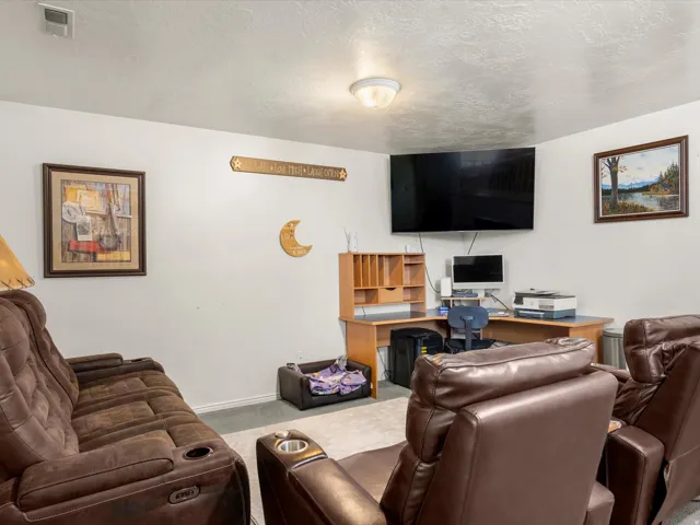 Versatile room featuring a built-in corner desk with integrated shelving, wall-mounted television, and flush-mount ceiling light fixture