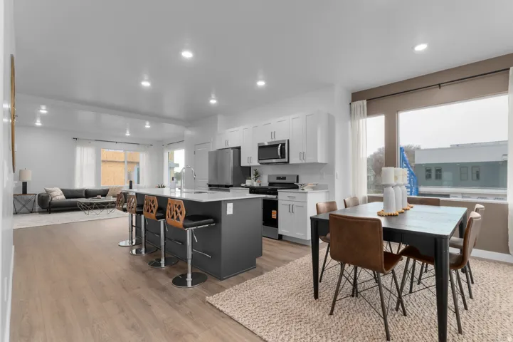 Open-concept living area featuring wood-finish flooring, recessed lighting, and large windows