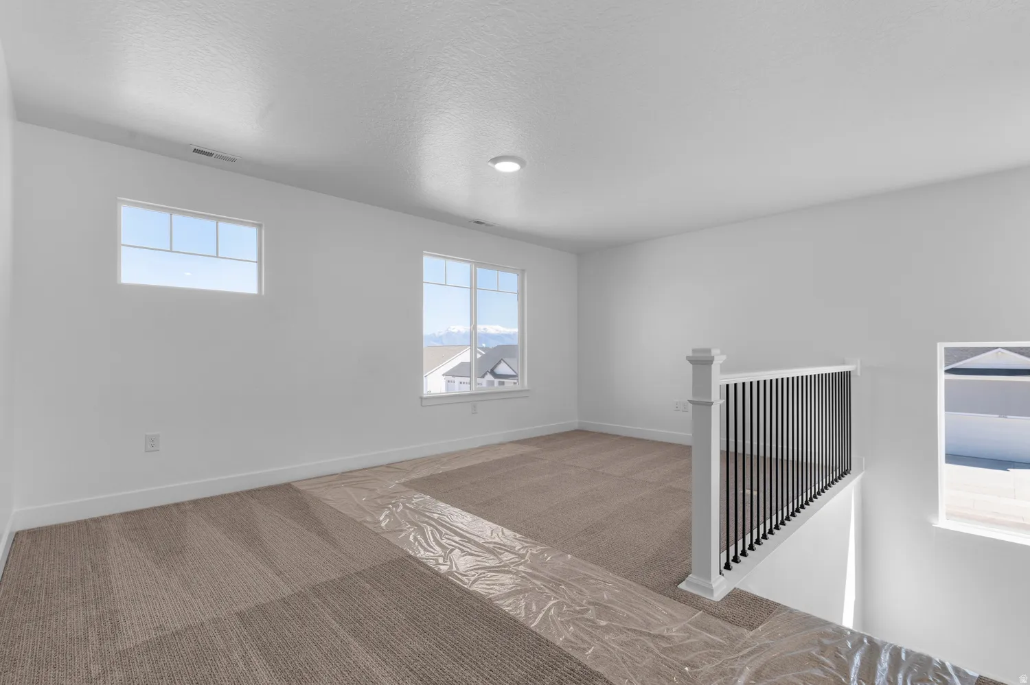 Carpeted loft area featuring white walls, recessed lighting, and multiple windows