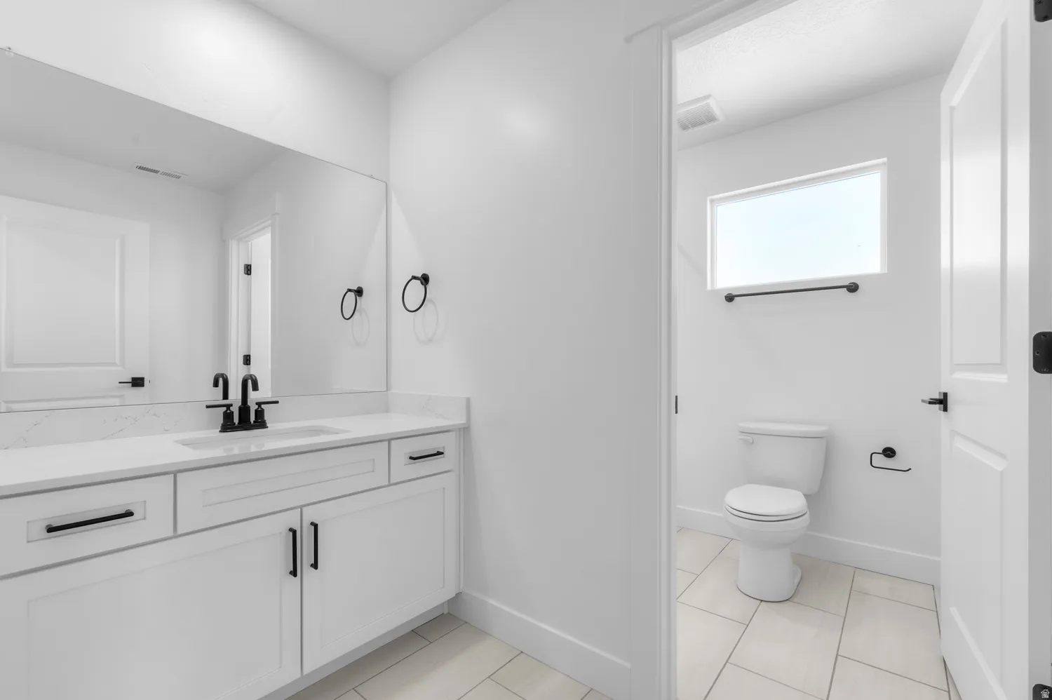 Contemporary bathroom featuring a white vanity with an integrated sink, quartz countertop, and matte black fixtures