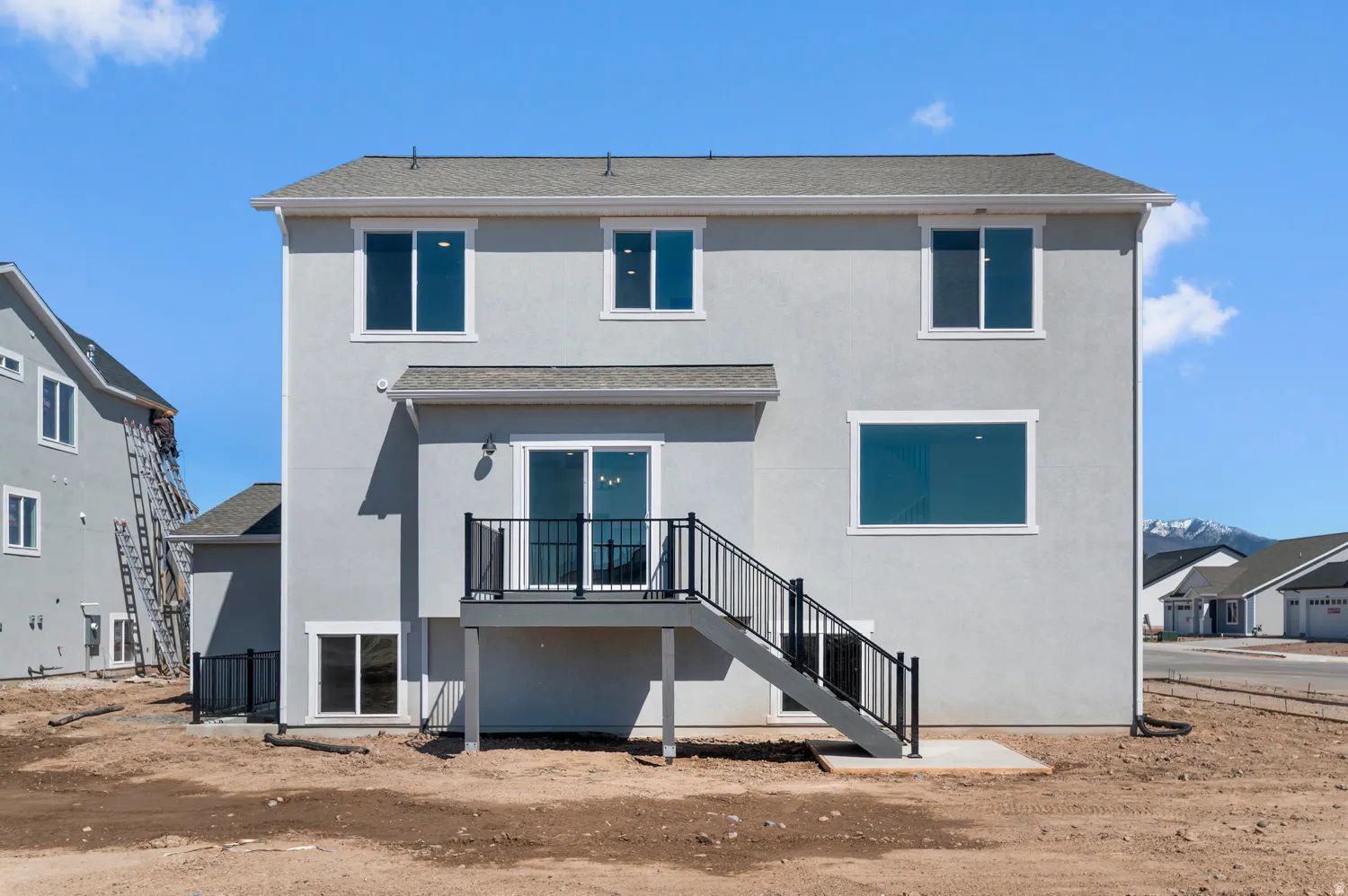 Rear elevation featuring a gray stucco finish and a gray shingle roof
