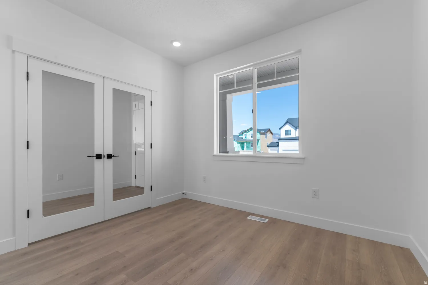 Room featuring wood-finish flooring, white walls, and a recessed ceiling light