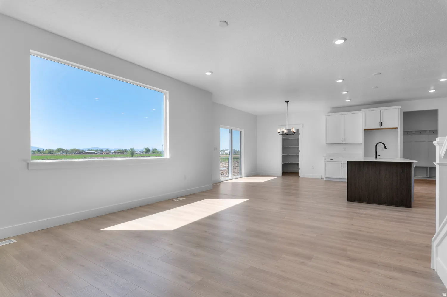 Spacious open-concept living area featuring light wood-finish flooring, a large picture window, and recessed lighting