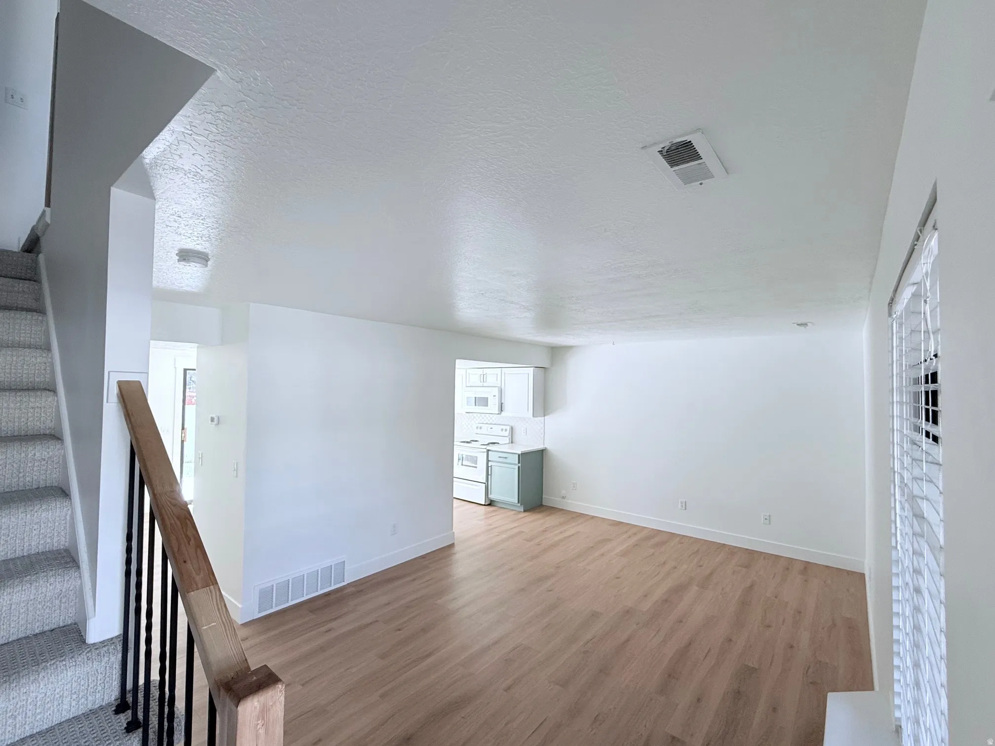 Wood-finish flooring, white walls, white window blinds, and recessed lighting
