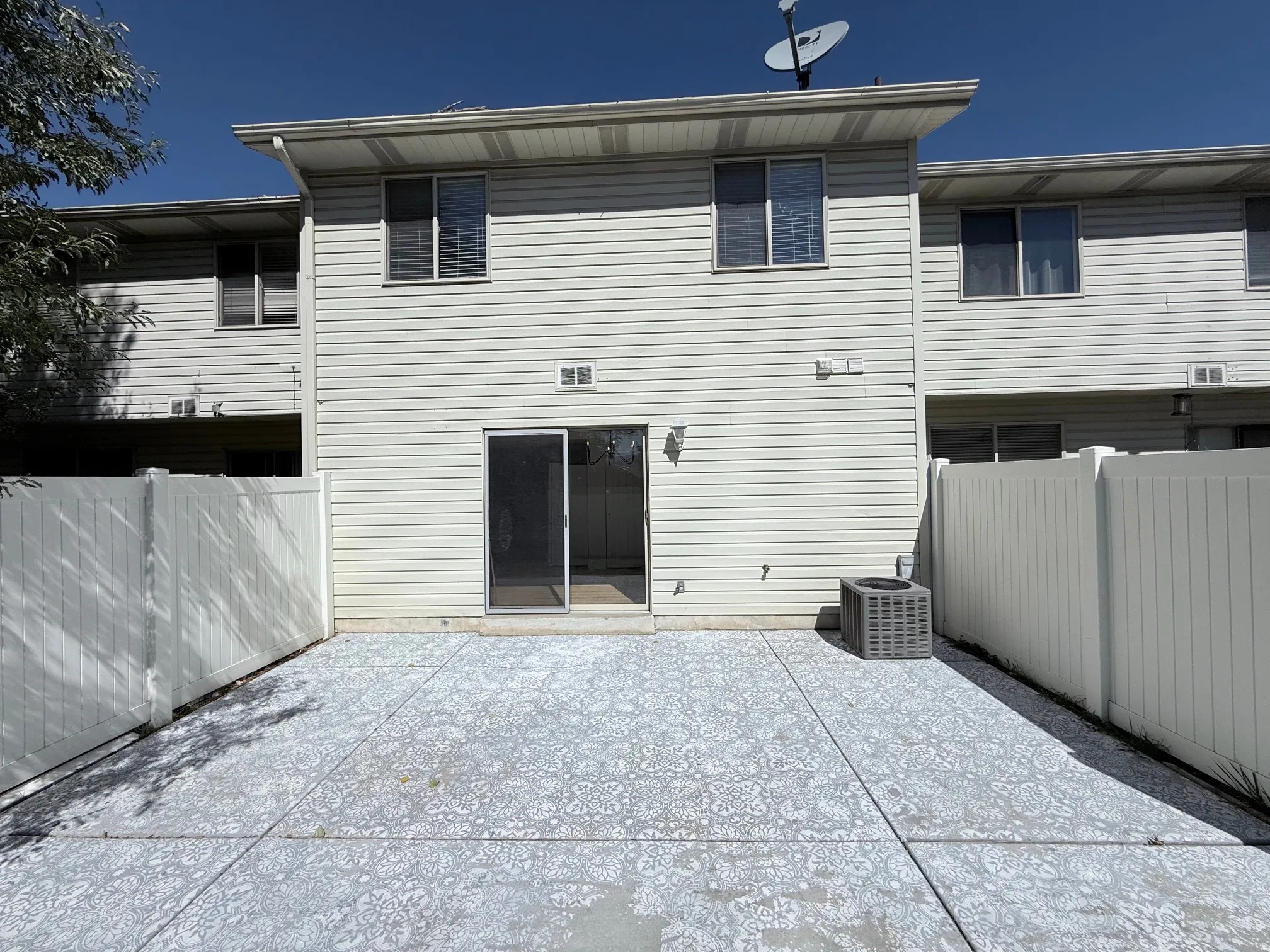 Spacious patio featuring light-colored concrete pavement, bordered by metal fencing on both sides
